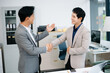 © laddawan - Asian Businessmen Shaking Hands, Analyzing Financial Reports in Modern Office