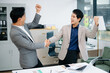 © laddawan - Two Asian businessmen in smart suits shake hands and analyze tax, report, and finance data using tablets and documents in a modern office setting.