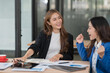© Thitisak - Two Asian businesswomen happily express their joy at the office.