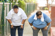 © GAJENDRRA BHATI  - Obesity- overweight exhausted indian couple stopped after jogging in summer park. Asian fat man and woman relaxing after exercise. Tired Plus size people trying to lose weight.