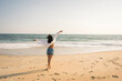 © Westend61 - Woman dancing playfully on a sunny beach with raised arms