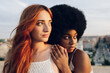 © Westend61 - Redhead woman looking away with young lesbian Afro girlfriend