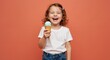 © NN AI - Smiling girl with curly hair holding mint ice cream cone on orange background. Child in white shirt and denim jeans enjoying frozen treat. Summer refreshment and happiness concept. Frozen dessert sale