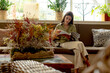 © we.bond.creations - Young woman enjoying reading a magazine while relaxing on a comfortable sofa in a bright and cozy home interior with natural light and plants