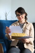 © Andrii Zastrozhnov - Young caucasian female smiling while opening mail in living room