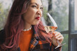 © EdNurg - Young woman grimacing while smelling a glass of spoiled bad wine, clearly expressing disgust at the unpleasant aroma and quality