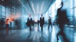 © ngalong project - Blurred figures walk in a modern office building with glass walls and reflective floor.
