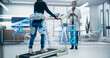 © Gorodenkoff - Woman Wearing Exoskeleton Uses a Treadmill for Physical Therapy, Monitored by Doctor. Advanced Neuralink Technology, Holographic Data Interface Shows Futuristic Healthcare and Rehabilitation Progress