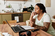 © Bliss - Woman engaged in remote work carefully studies her laptop while sipping tea at home