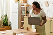 © Bliss - Focused young woman engages in remote work from her cozy kitchen workspace