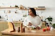 © Bliss - Young African American woman preparing a fresh salad while enjoying cooking at home