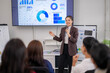 © Wasana - A woman is giving a presentation in front of a group of people