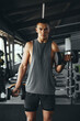 © Davidovici - Vertical photo of attractive bodybuilder man in sportswear lifting weights at modern gym. Bodybuilding, fitness and health care concept.