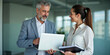 © budistwn - Busy professional smiling businessman and businesswoman leaders having conversation at work. Executives team of two business people working talking using laptop technology standing in corporate office