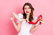 © deagreez - Young woman holding two colorful high heels looking perplexed against a pink background