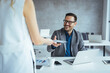 © Dragana Gordic - Smiling Businessman Receiving Document in a Modern Office Workspace