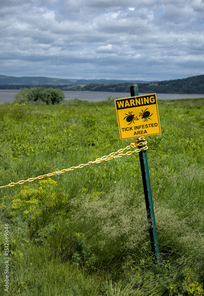 Infested Area. Sign warning tick infested area sign in grassy area near the hudson river ...