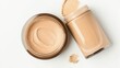 © Julia - Makeup cosmetics are showcased in a photograph of a glass bottle and jar of beige foundation on a white background from a top view