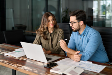 middle aged female manager teaching young male worker looking at computer discussing ai online busin