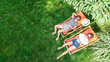 © Iuliia Sokolovska - Young girls relax in summer garden in sunbed deckchairs on grass, women friends have fun outdoors in green park on weekend, aerial drone view from above