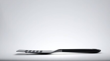 A modern, stainless steel spatula lies on a plain background