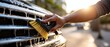© Fernando - Closeup of an adult hand using a brush to clean the soapy chrome grill of a car outdoors in the bright sunlight Concept of car detailing and maintenance