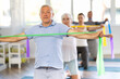 © JackF - Group of elderly people doing arm stretching exercises using resistance bands while kneeling on mats