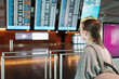 © ArinaDvl - A young female traveler checks the airport departure board wearing a backpack. Concept of travel planning and journey anticipation.