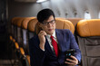 © NVB Stocker - Business trip vacation and travel concept. Asian business Man travelling by plane and using mobile phone