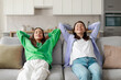 © Home-stock - Calm and relaxed mom and teenage daughter chilling on couch hands over head, resting with eyes closed and dreaming