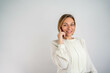 © Nenad - Cheerful business lady. Beautiful mature businesswoman talking on her smartphone and looking at camera with smile while standing against white background