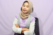 © Ayudia - Young asian muslim woman standing with confidence, pointing gesture against purple isolated background