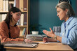 © Mediaphotos - Middle aged Caucasian female social worker discussing paperwork with young adult Caucasian woman in office setting, engaging in supportive conversation and providing assistance