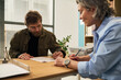 © Mediaphotos - Middle aged Caucasian woman social worker helping middle aged Caucasian man complete social services paperwork at desk in modern office setting, both focused on documents