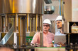 © NVB Stocker - Wine production line : Twe engineering and factory worker in sterile uniform working checking industrial machine in wine factory