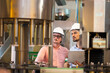 © NVB Stocker - Wine production line : Twe engineering and factory worker in sterile uniform working checking industrial machine in wine factory