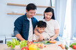 © Q88 - Family preparing a healthy meal together with a young boy slicing vegetables under supervision