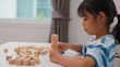 © FAMILY STOCK - Young Asian girl focused on stacking wooden blocks, promoting STEM learning, creativity, and motor skill development. Concept of early education, problem solving, and cognitive growth.