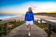© Jacek Chabraszewski - Beautiful mature woman walking up stairs with sandy beach in background. Front view. Amoreira Praia in Algarve, Portugal