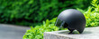 © IndigoElf - A black helmet with a visor sits on a stone ledge surrounded by greenery. Safety gear concept