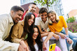 © Xavier Lorenzo - Young happy group of diverse friends laughing while using mobile phone at city street, enjoying social media content