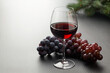 © Totabof - Elegant Red Wine Glass with Fresh Grapes on Textured Surface