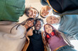 © Lomb - Diverse group of young people smiling in circle from below, expressing unity and authentic friendship