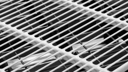 Poster - A close up of a white grill with black holes in it. The grill is made of metal and has a mesh pattern. The image has a minimalist feel to it, with the focus on the grill's design