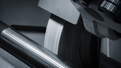 Poster - Industrial sharpening machine with large abrasive white disc close-up sharpening round metal part, industrial conceptual background