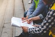 © aFotostock - Asian engineer man brainstorming construction building contractor civil worker parners team meeting at constrcution site. Blueprint engineer hardhat worker helmet on table. Engineer teamwork consult