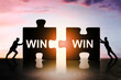 © Who is Danny - Two people pushing puzzle pieces labeled 'WIN' together under sunset sky symbolizing teamwork, unity, and win-win concept in business collaboration.