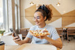 © Dusan Petkovic - Portrait of cheerful trendy interracial girl sitting in fast food restaurant with pizza in hand and texting messages on her cellphone.