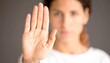 © Marko - woman showing stop gesture with hand raising up on black background, young female protesting against domestic violence and abuse, bullying