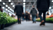 © Nakarin - People walking in indoor market or exhibition hall with plants on display, creating lively and bustling atmosphere, with bright overhead lighting and blurred background